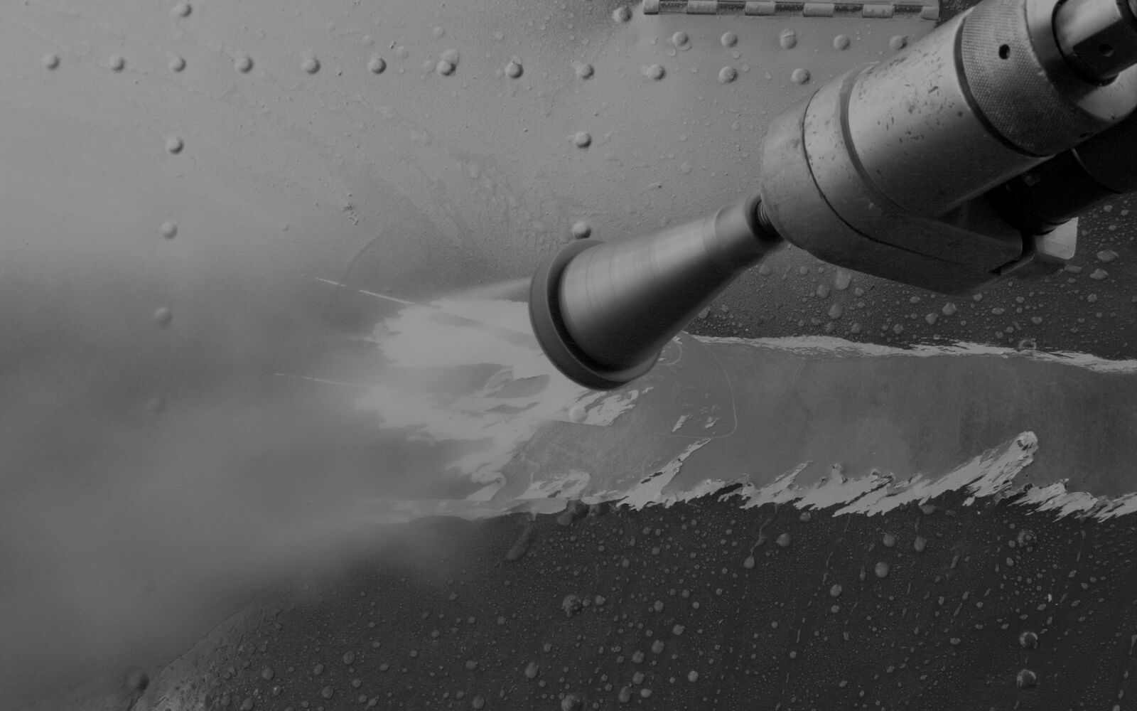 A jetting nozzle lifting paint away from riveted aircraft skin