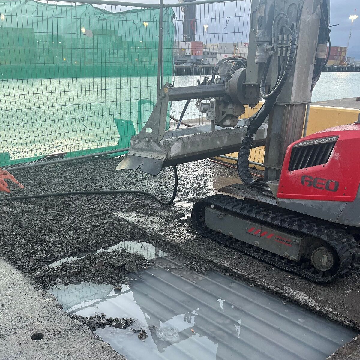 A tracked hydrodemolition robot cutting asphalt and concrete on a port wharf